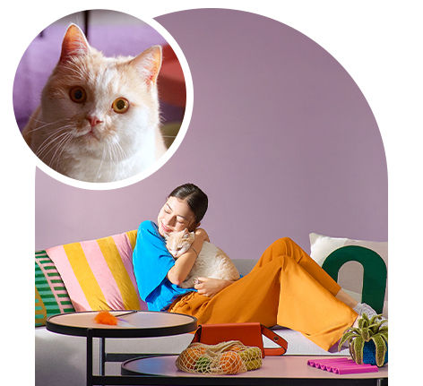 A young girl hugs a cat as she relaxes on a couch. A close-up of the cat's face is at the top left.
