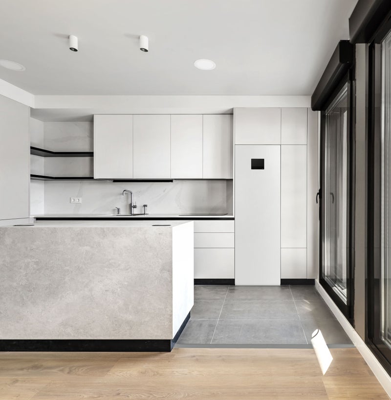 2247371583 Newly installed modern kitchen with central island, smooth gray cabinets, black glass appliances and glass-covered wall with access to an open terrace